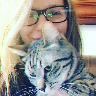 Photo of author Kristen Casey wearing glasses and holding a tabby cat.